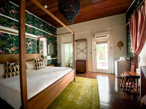 a bedroom with a canopy bed with floral wallpaper at Marreros Guest Mansion - Adult Only in Key West