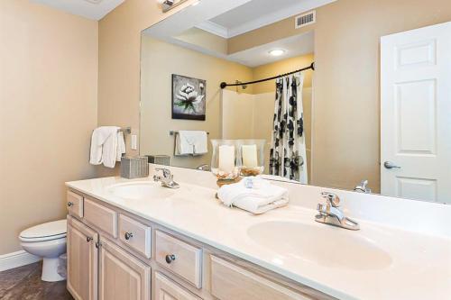 a bathroom with a sink and a toilet and a mirror at Crystal Shores West II in Gulf Shores