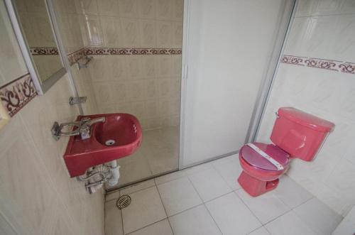 W łazience znajduje się czerwona toaleta i umywalka. w obiekcie Hotel Central w mieście Puebla