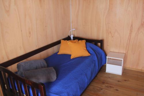 a bed with a blue blanket and a chair in a room at Santo Descanso in Punta Del Diablo