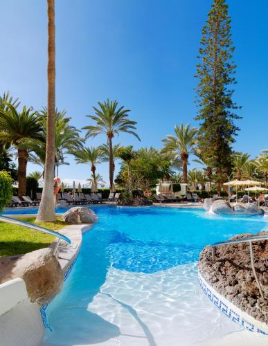 a swimming pool at a resort with palm trees at Boutique Hotel H10 Big Sur - Adults Only in Los Cristianos