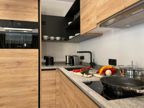 una cocina con armarios de madera y verduras en la encimera en HAUSZEIT APPARTEMENTS en Haus im Ennstal