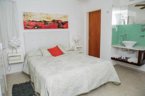 Dormitorio blanco con cama con almohada roja en Complejo Turístico Las Catalpas, en Mina Clavero