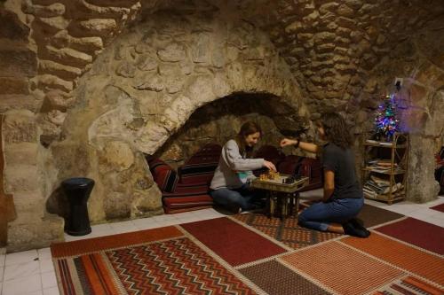 dos personas están jugando un juego en una sala de piedra en New Citadel Hostel, en Jerusalén