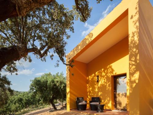 a yellow house with three black chairs on the porch at Monte da Esperanca in Esperança