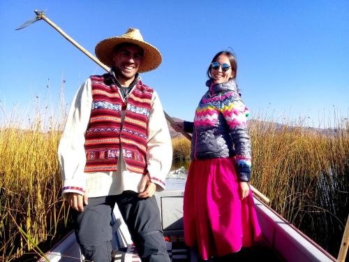 een man en een vrouw staan op een boot bij Lago Titicaca in Puno