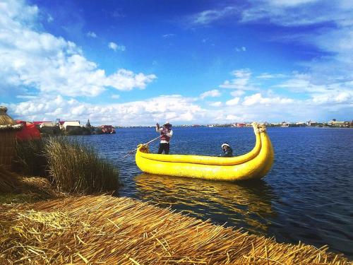 een man die in een grote bananenboot op het water staat bij Lago Titicaca in Puno