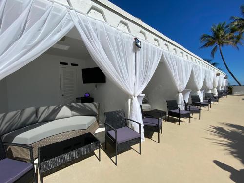 a row of beds on the beach with white curtains at The Alexander Beach Residences in Miami Beach