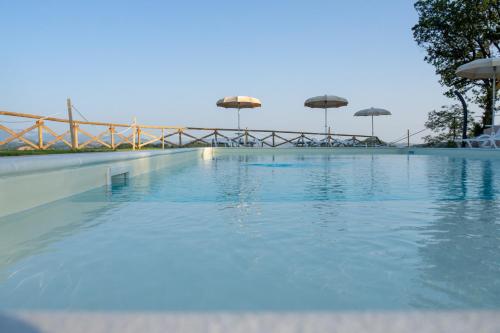 a large swimming pool with umbrellas on top of it at Country House Ca'Balsomino in Urbino