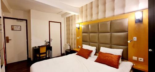 a bedroom with a large white bed with orange pillows at Hotel de France 18 in Paris