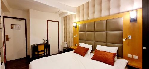 パリにあるオテル ド フランス 18のベッドルーム(オレンジ色の枕が付いた大きな白いベッド付)