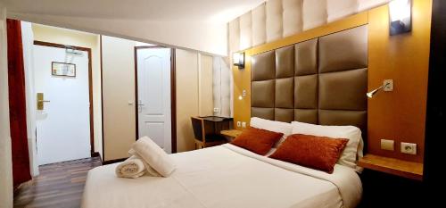 - une chambre avec un grand lit blanc et des oreillers orange dans l'établissement Hotel de France 18, à Paris