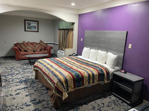 a hotel room with a bed and a couch at Scottish Inn and Suites Alvin in Alvin