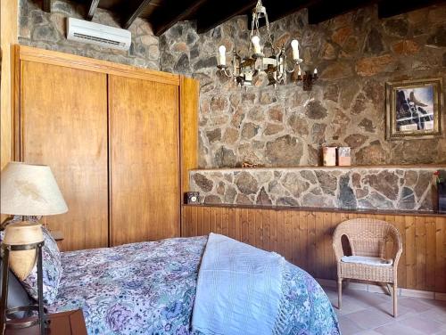 1 dormitorio con cama y pared de piedra en casa rural LA LIMERA con piscina privada, en Santa Lucía