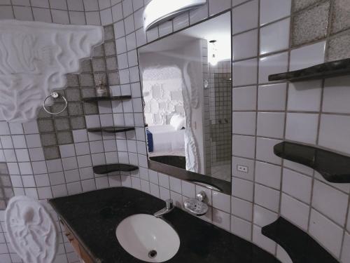 a bathroom with a sink and a mirror at Suítes Bela Vista in Japaratinga