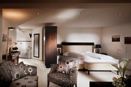 a bedroom with a large bed and a chair at Waldhotel Doldenhorn in Kandersteg