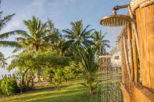 a fence with palm trees in the background at Tai Marino Beach Bungalows in Amuri