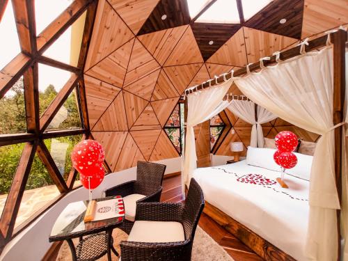 a bedroom in a tree house with a bed and chairs at Hotel Campestre La Periquera in Villa de Leyva