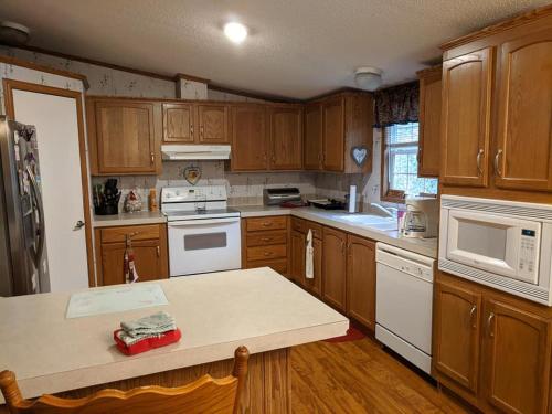 una cocina con armarios de madera y electrodomésticos blancos en Thomas Holiday Home, en Clearfield