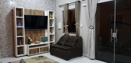 a living room with a chair and a television at Casa confortável com piscina compartilhada in Aracaju