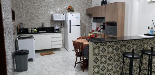 a kitchen with a refrigerator and a table and chairs at Casa confortável com piscina compartilhada in Aracaju