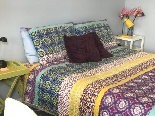 ダニーデンにあるCosy Caversham Retreatのベッド(カラフルな毛布、枕付)