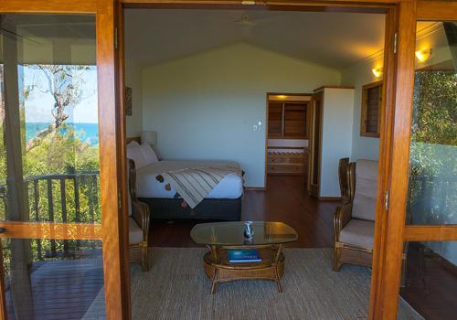 a room with a bed, chair, table and a window at Thala Beach Nature Reserve in Oak Beach