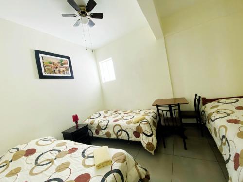 a room with two beds and a ceiling fan at Lima House Hostel in Lima