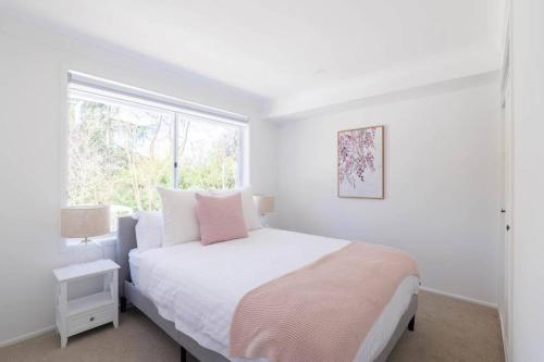 a white bedroom with a bed and a window at Abbey House - 3BR/sleeps 8 - South Leura in Leura
