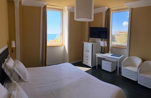 a bedroom with a bed and a desk and windows at Greif Hotel Maria Theresia in Trieste