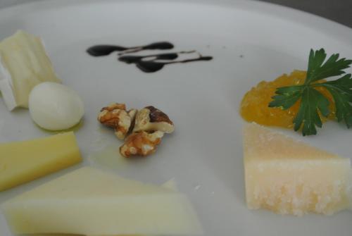 a white plate with cheese and other foods on it at Hotel Bologna in Lignano Sabbiadoro