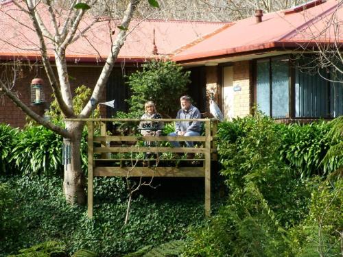 a man and woman sitting on a fence in front of a house at Adelaide Hills B&B Accommodation in Stirling