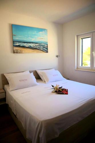 a bedroom with a white bed with flowers on it at Restful Kanica House in Rogoznica