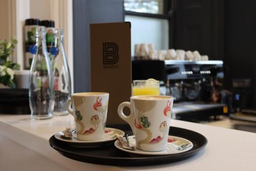 two coffee cups sitting on a tray on a counter at Orange Grove Hotel & Gardens in Southampton