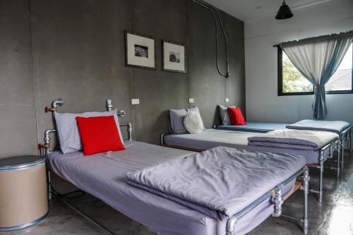 een groep bedden in een kamer met een raam bij Patoey House in Chon Buri