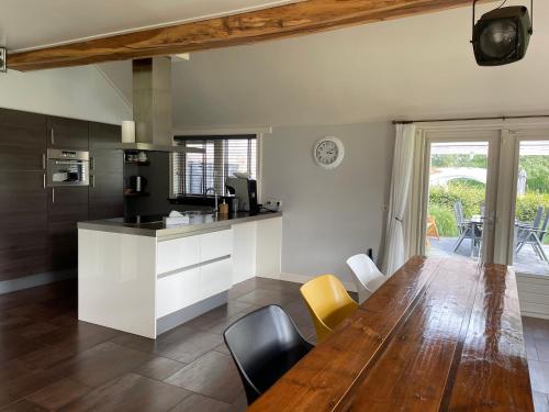 een keuken en eetkamer met een houten tafel en stoelen bij De Boerderij - Buitenplaats Ruitenveen, privé in Nieuwleusen
