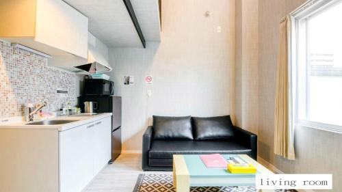 a living room with a black couch and a kitchen at Aparthotel Palais Royal with Parking in Sapporo