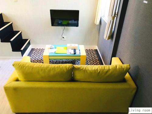 - un canapé jaune dans le salon avec une table dans l'établissement Aparthotel Palais Royal with Parking, à Sapporo