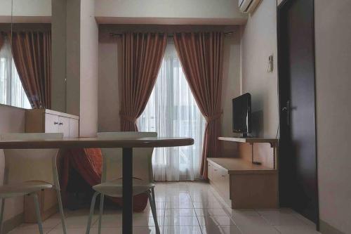 a room with a table and chairs and a television at Apt 2 BR Sunter Park View With Pool and Netflix in Jakarta