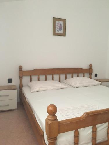 una camera con letto in legno e lenzuola bianche di Apartmani Belobrk Potocnica Pag a Potocnica