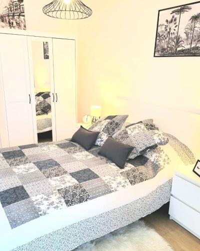 une chambre avec un lit avec une couette noire et blanche dans l'établissement 1 APPART 2 PIECES NEUF PROCHE GARE PARKING NETFLIX Evry Courcouronnes, Évry-Courcouronnes