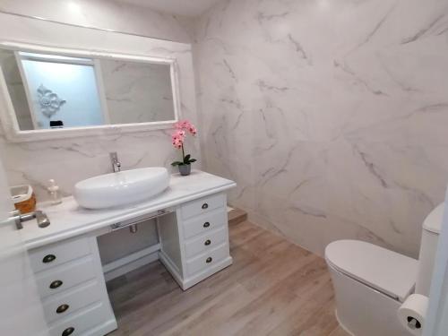 een witte badkamer met een wastafel en een spiegel bij Gelvesturist 2 in Gelves
