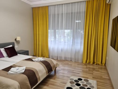 a bedroom with two beds and a window with yellow curtains at City Inn Premium Apartment 2 in Timişoara