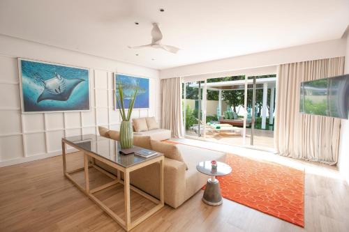 a living room with a couch and a table at Emerald Maldives Resort & Spa-Deluxe All Inclusive in Raa Atoll