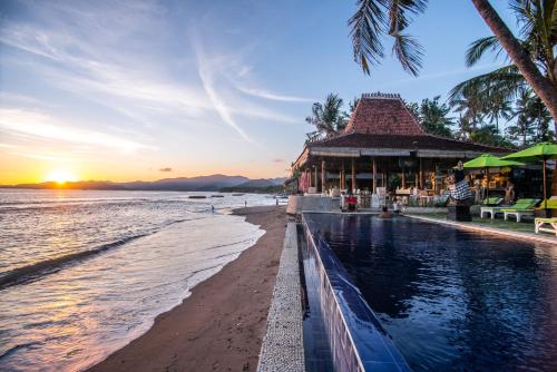 a resort with a pool and a beach at sunset at Bali Santi Bungalows in Candidasa