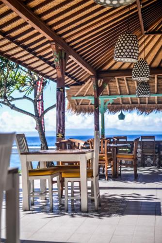 a table and chairs under a pavilion on the beach at Bali Santi Bungalows in Candidasa