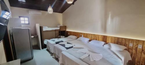 a bedroom with two beds with white pillows at Pousada Lua Nova Charmosa Pipa in Pipa