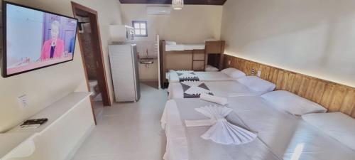 a room with white couches and a flat screen tv at Pousada Lua Nova Charmosa Pipa in Pipa