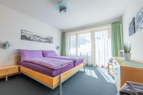 una camera con letto viola e finestra di Apartments Saasunia a Saas-Grund