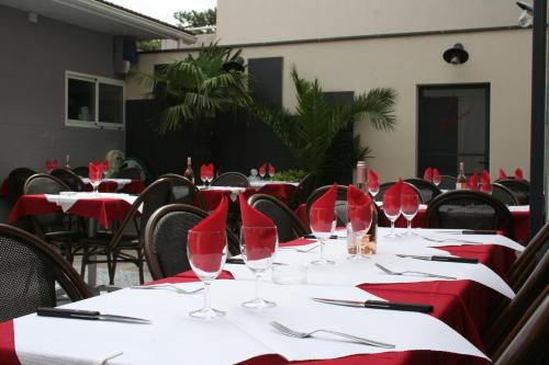 a group of tables with red napkins and wine glasses at Hôtel Les Italiens in Biscarrosse